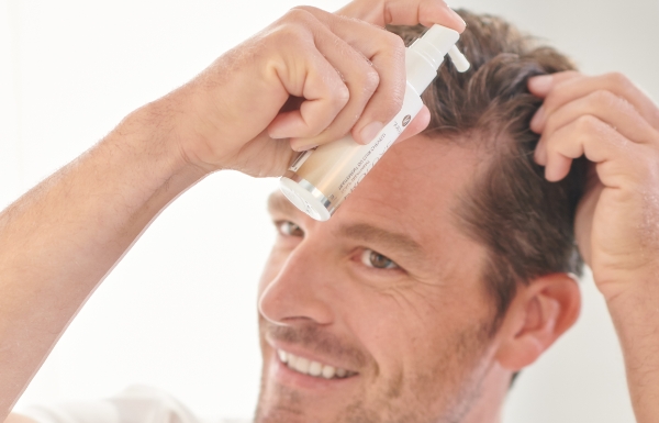 A man sprays ProLuxe Scalp Treatment into his hairline and scalp.
